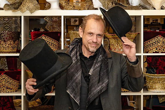 Gerzy Keszler mit zwei Hüten in seinem Kostümfundus.