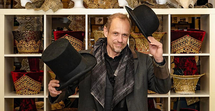 Gerzy Keszler mit zwei Hüten in seinem Kostümfundus.