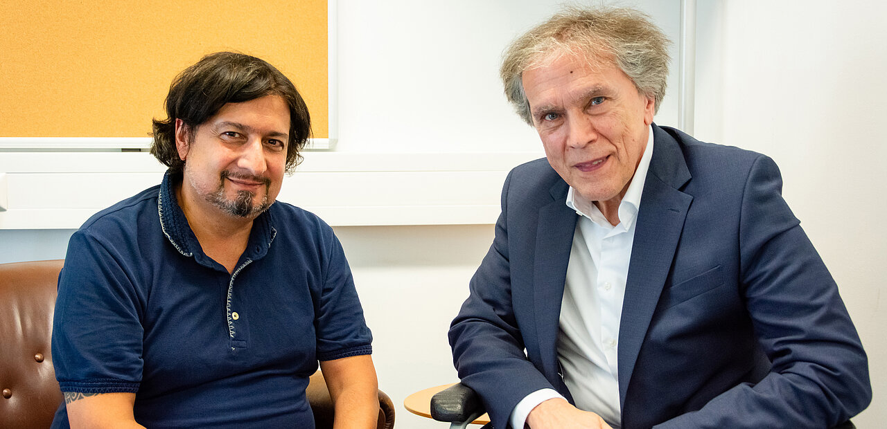 Stefan Hauser im Gespräch mit Botschafter Emil Brix. Aufgrund einer Erkrankung ist der Rollstuhl ein wichtiges Fortbewegungsmittel.