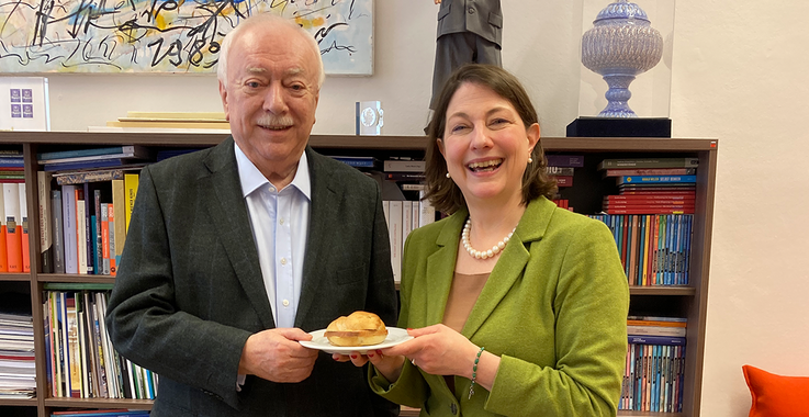 Michael Häupl (links) mit Sophie Lauringer (rechts), gemeinsam einen Teller mit einer Leberkäsesemmel haltend.