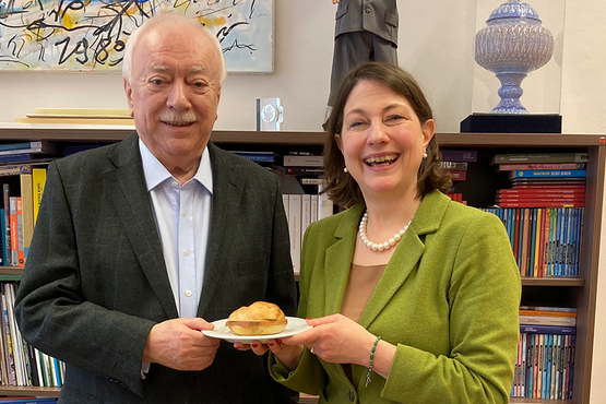 Michael Häupl (links) mit Sophie Lauringer (rechts), gemeinsam einen Teller mit einer Leberkäsesemmel haltend.