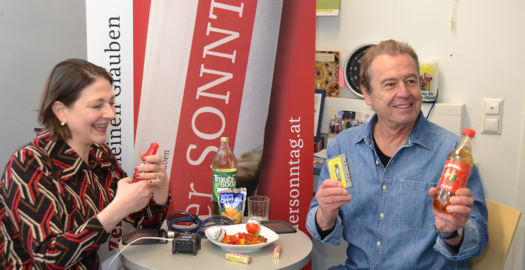 Sophie Lauringer und Udo Huber mit Süßigkeiten in der Hand, lachend.
