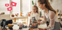 Symbolbild Hausfrau mit Kind in der Küche, Videokamera, die alles filmt