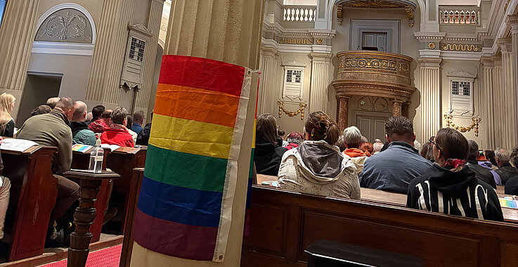 Die Regenbogenfahne in der Kirche als Zeichen queerer Menschen.
