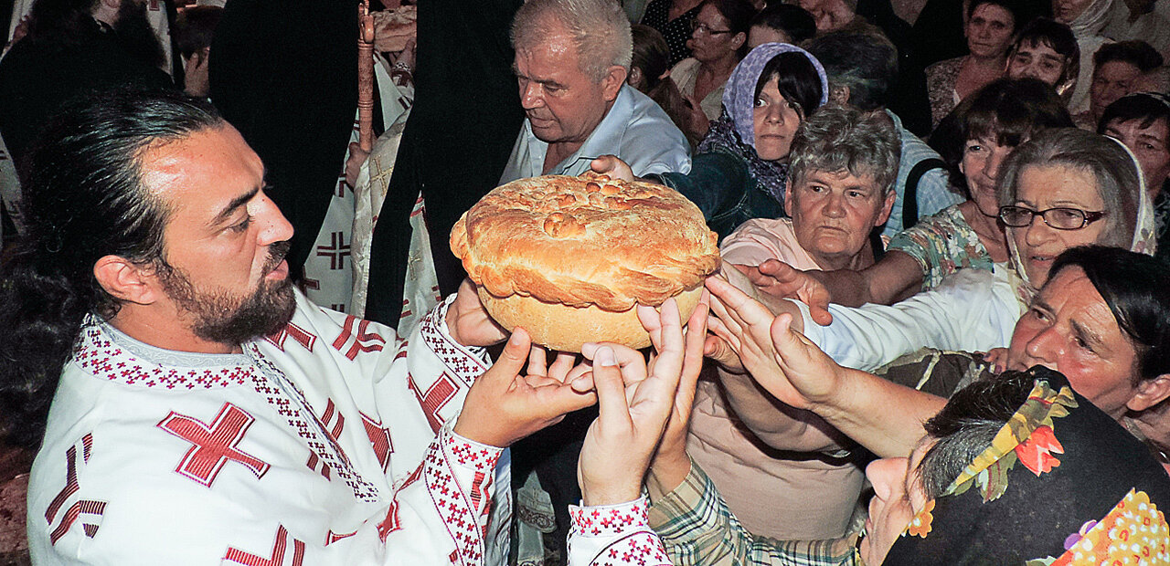 Der „Slavski Kolač“, ein Festtagskuchen, wird von dem serbisch-orthodoxen Priester und dem Volk gehalten und mit kleinen Bewegungen gedreht – Zeichen der Einheit und der Ewigkeit (Kloster Krupa, Kroatien).