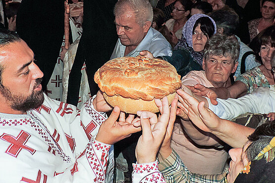 Der „Slavski Kolač“, ein Festtagskuchen, wird von dem serbisch-orthodoxen Priester und dem Volk gehalten und mit kleinen Bewegungen gedreht – Zeichen der Einheit und der Ewigkeit (Kloster Krupa, Kroatien).