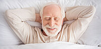 Mann liegt mit Pyjama im Bett