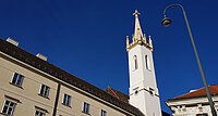 Der weithin sichtbare Kirchturm von Sankt Augustin, im Schatten der Wiener Hofburg.