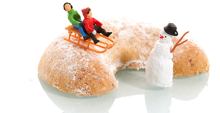 großes Vanillekipferl mit Figuren: zwei Kinder mit der Rodel und ein Schneemann