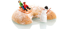 großes Vanillekipferl mit Figuren: zwei Kinder mit der Rodel und ein Schneemann