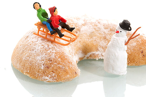 großes Vanillekipferl mit Figuren: zwei Kinder mit der Rodel und ein Schneemann