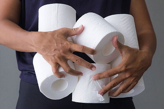 Person hält viele Rollen Klopapier.