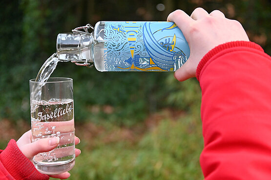 Wasser wird in Glas eingeschenkt