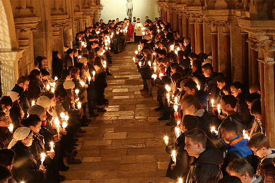 Jugendliche mit Kerzen im Kreuzgang