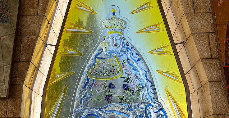 Ein besonderes Detail  vor der Verkündigungskirche ist eine Darstellung der Magna Mater Austriae, der Gnaden-statue von Mariazell, in einem gelben Glasfenster. 