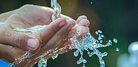 Hände, die, zu einer Schale geformt, frisches Wasser aufnehmen