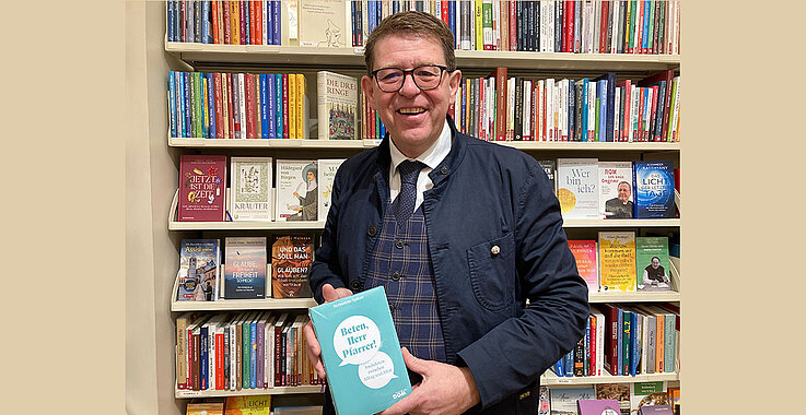 Buchhändler Werner Riedmüller zeigt das Buch "Beten, Herr Pfarrer"