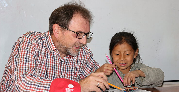 Reinhard Heiserer lernt mit einem kleinen Mädchen.