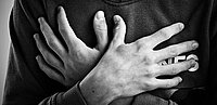 Sich überkreuzende, vor der Brust einer Person verschränkte Hände.