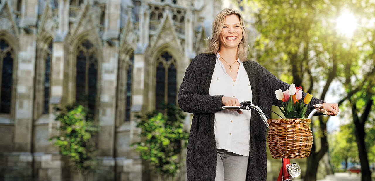 Frau mit Fahrrad vor Kirche in der Frühlingssonne