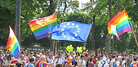 Regenbogenflaggen und eine EU-Flagge bei einer Demonstration.