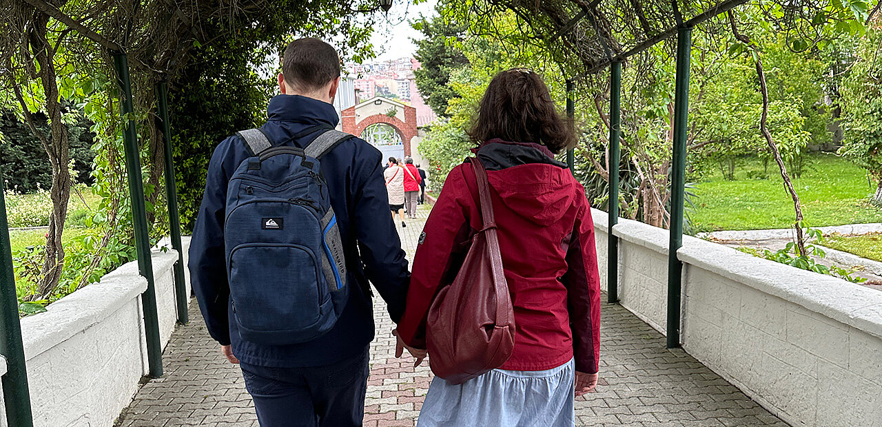 Pärchen geht Hand in HAnd durch einen Laubengang