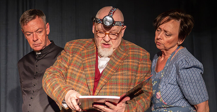 Jürgen Pfaffinger als Pater Brown mit zwei Schauspielkollegen auf der Bühne.