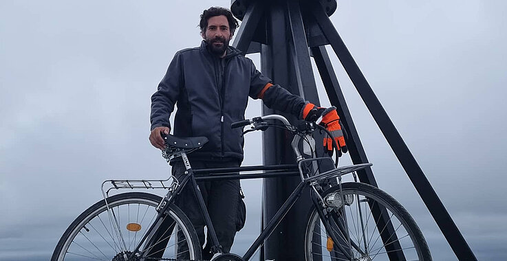 Ein Mann mit seinem Fahrrad am Nordkap. 