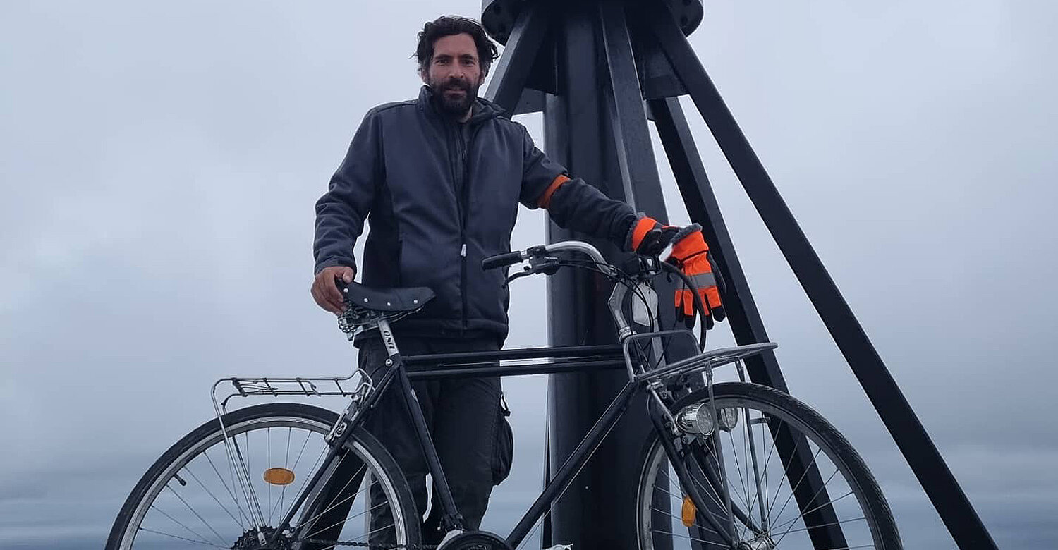 Ein Mann mit seinem Fahrrad am Nordkap. 