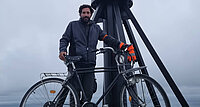Ein Mann mit seinem Fahrrad am Nordkap. 