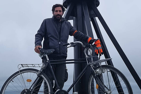 Ein Mann mit seinem Fahrrad am Nordkap. 