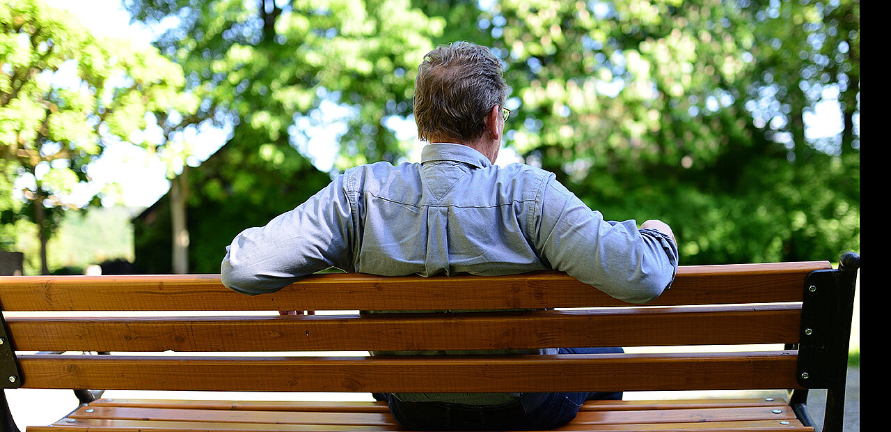Ein Mann sitzt auf einer Parkbank