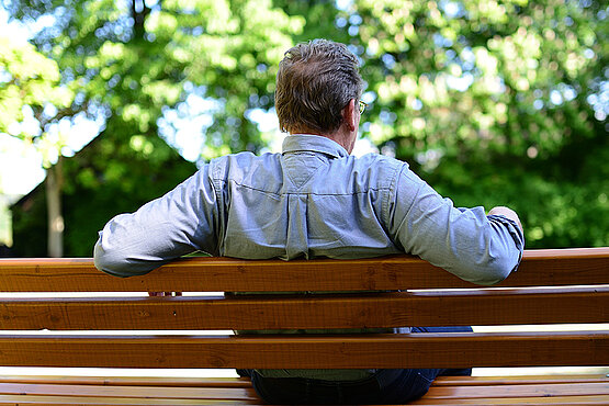 Ein Mann sitzt auf einer Parkbank