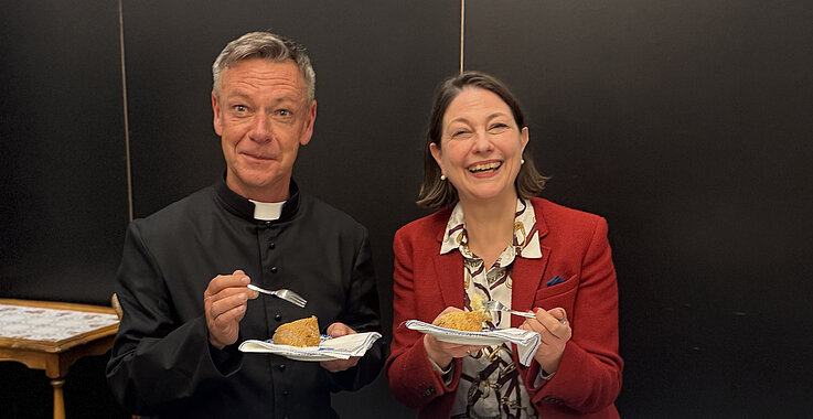 Jürgen Pfaffinger und Sophie Lauringer bei der Podcast-Aufnahme. Sie essen Kuchen.