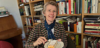 Susanne Kalss lächelt in die Kamera und isst einen Topfenstrudel.