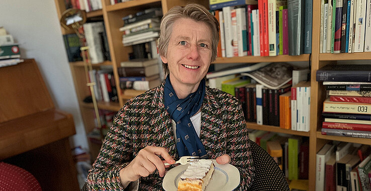 Susanne Kalss lächelt in die Kamera und isst einen Topfenstrudel.