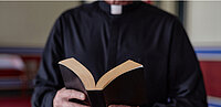Priester liest Bibel