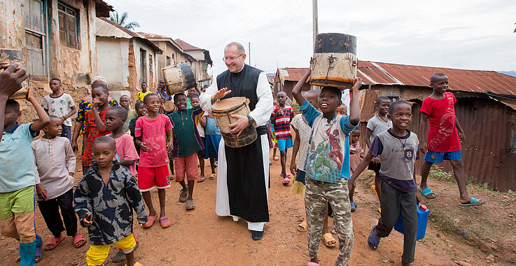Pater Karl Wallner mit Kindern trommelnd in Afrika
