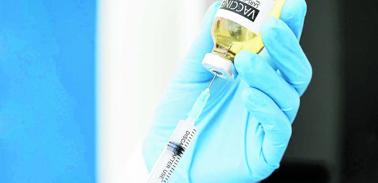 Corona Impfstoff wird in Spritze aufgezogen