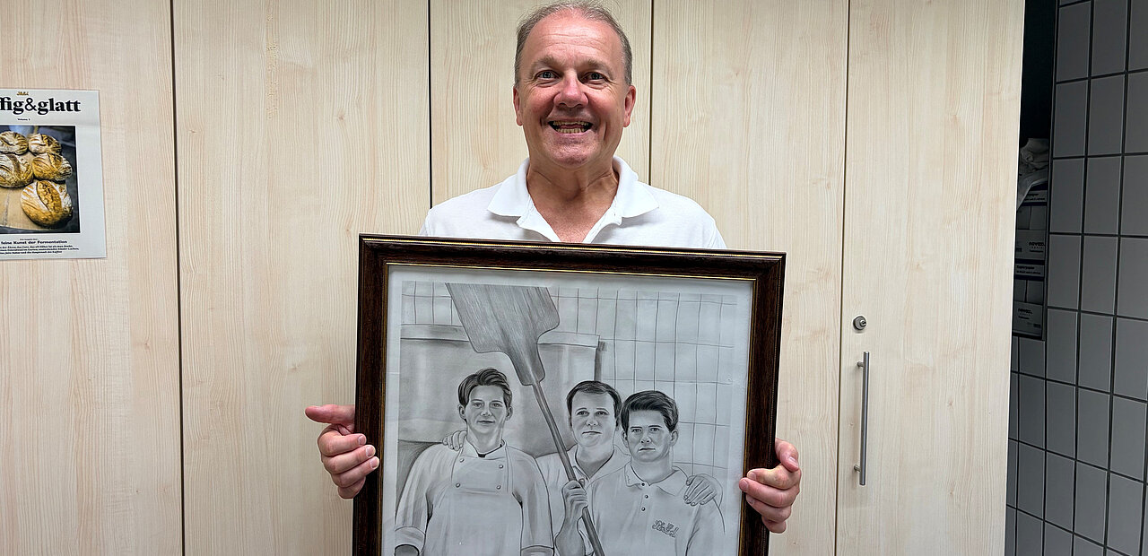 Unternehmer Gerhard Ströck mit einer Zeichnung von ihm und seinen Söhnen. Das Bild haben Mitarbeiter gemacht. 