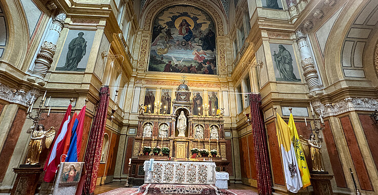 Der Hauptaltar der Kirche „Maria Schutz“. Das Bild von Camillo Sitte zeigt Maria mit dem Jesus-Kind in der Mitte, darunter ist ein Bild von Mechitar von Sebaste. Am linken Rand des Bildes kann man, erzählt uns Pater Vahan Hovagimian, den Berg Ararat in Armenien, auf dem die Arche-Noah liegt, erkennen. 
