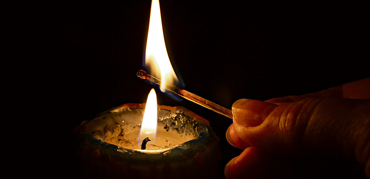 Eine Kerze wird mit einem Streichholz angezündet.