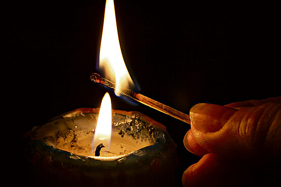 Eine Kerze wird mit einem Streichholz angezündet.