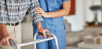 Care-Arbeit: Junge Pflegerin hilt altem Mann